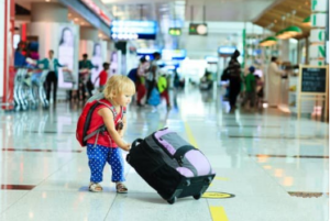A toddler gild with a luggag at the airport