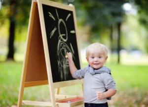 A toddler boy drawing on board